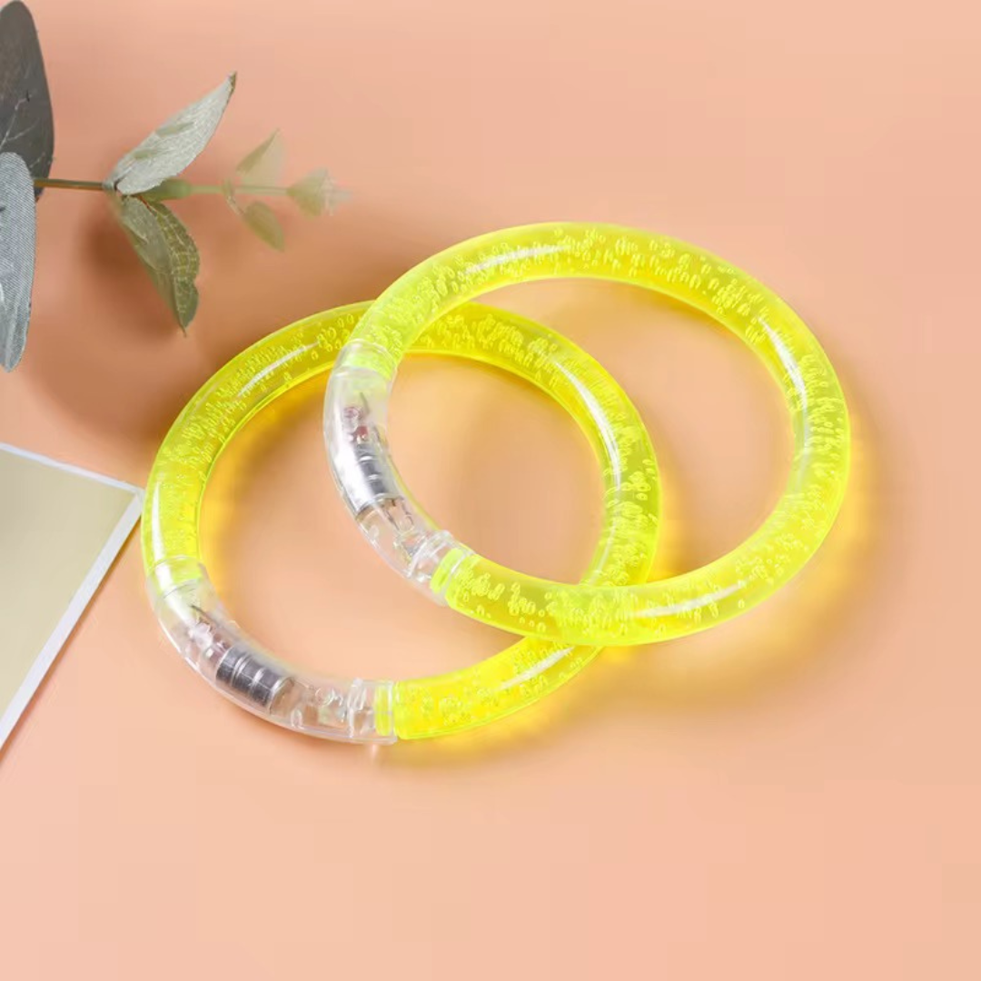 Two yellow and clear bracelets on a peach-colored background