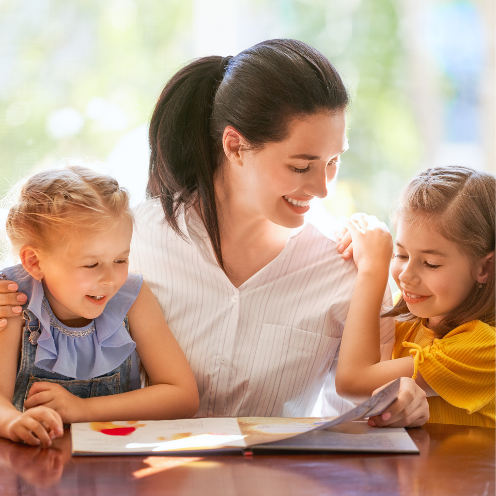 mom sitting on a desk with 2 children reading a book