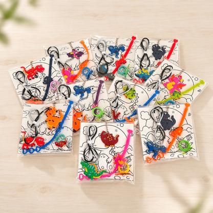 Set of 10 ready-made dinosaur party favors, individually packed with colorful dinosaur necklaces, bracelets, rings, keychains and coloring cards, displayed on a light wood table.