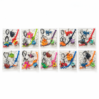 Ten individually packed dinosaur party favors arranged in two rows, each containing a necklace, bracelet, ring, keychain and dinosaur coloring card.