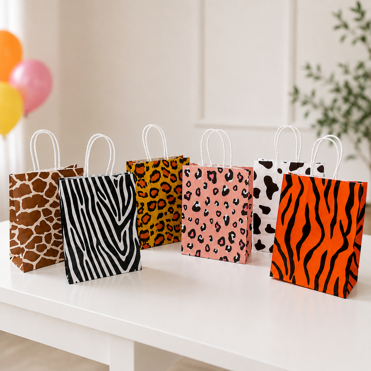 Animal print party favor bags displayed on a white table with colorful balloons in a bright birthday party setting.