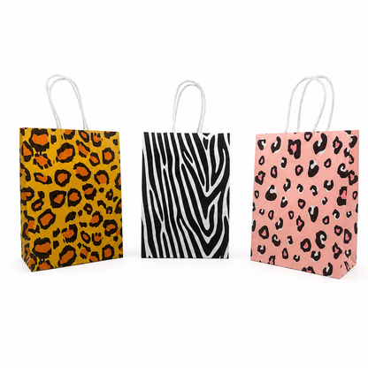 Three small paper gift bags with white twisted handles, shown side by side on a white background. The left bag has a yellow, black, and orange leopard print.