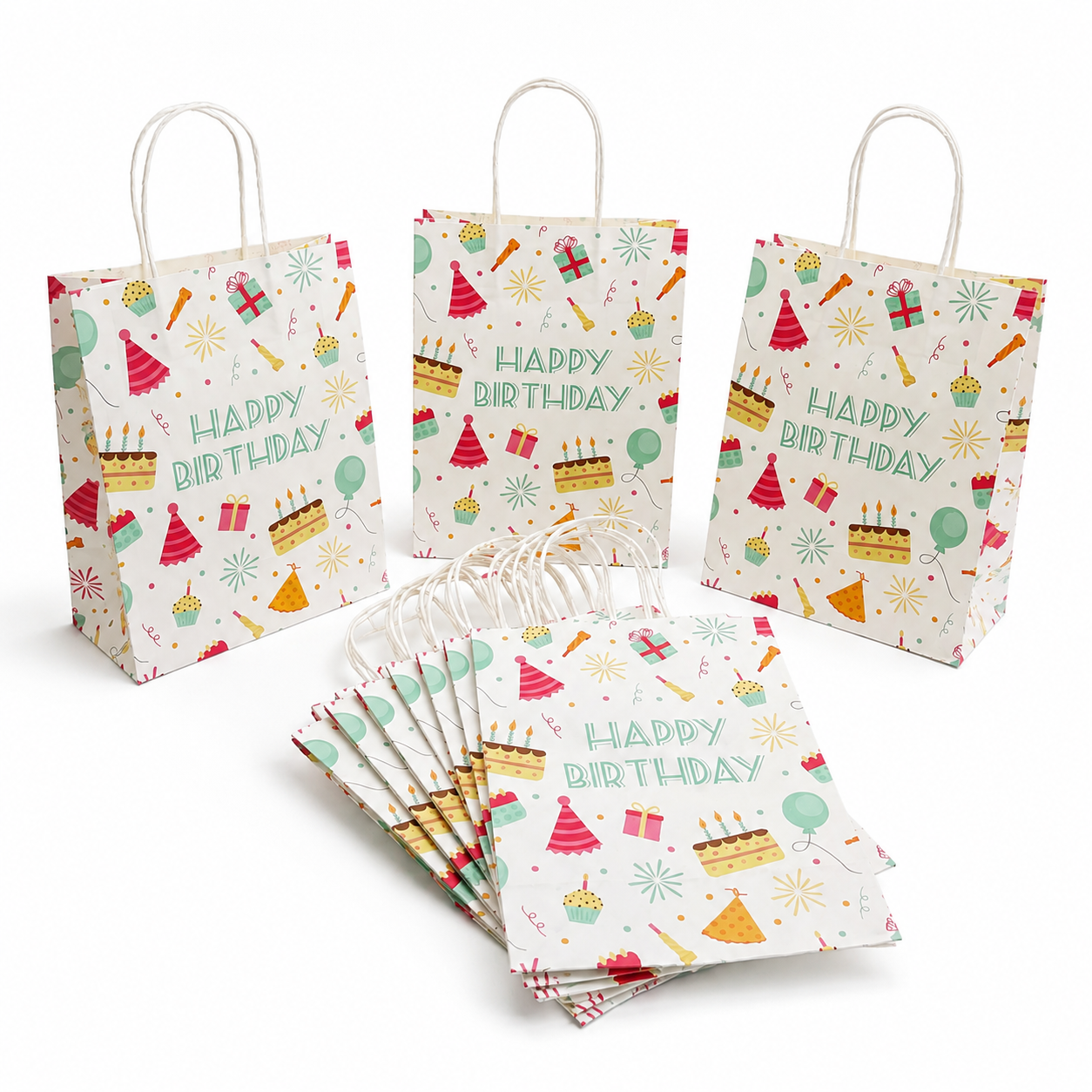 A set of white paper party bags with white handles, decorated with colorful 'Happy Birthday' illustrations including cakes, balloons, party hats, and fireworks. One bag stands upright on the left, two stand upright on the right, and a fan of bags lies in the foreground on a clean white background.