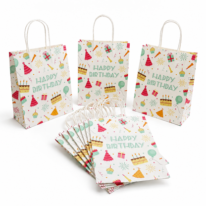 A set of white paper party bags with white handles, decorated with colorful 'Happy Birthday' illustrations including cakes, balloons, party hats, and fireworks. One bag stands upright on the left, two stand upright on the right, and a fan of bags lies in the foreground on a clean white background.