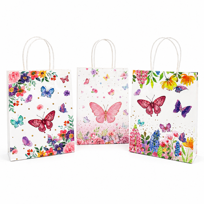Three white paper gift bags with white handles, decorated with colorful watercolor-style butterflies and floral designs, shown on a light gray background.